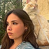 woman, cat, outdoor, striped_shirt, bench, greenery, sunlight, portrait, pet, fluffy_cat, calm, thoughtful, earrings, long_hair, wall, nature, relaxed, daylight, side_profile, leash