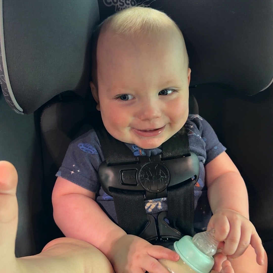 Prometheus joined the competition — help win amazing prizes! baby, car_seat, milk_bottle, smiling, child, infant, safety_harness, foot, hand, blue_shirt, inside_car, seatbelt, cute, happy, cheeky, skin, head, person, young_child, playful