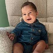 Elio a rejoint le concours — aidez-le/la à gagner de superbes lots ! baby, child, denim_shirt, smiling, happy, sitting, armchair, furniture, cozy, indoor, soft_light, cute, infant, portrait, person, comfortable, home, fabric, foot, hand
