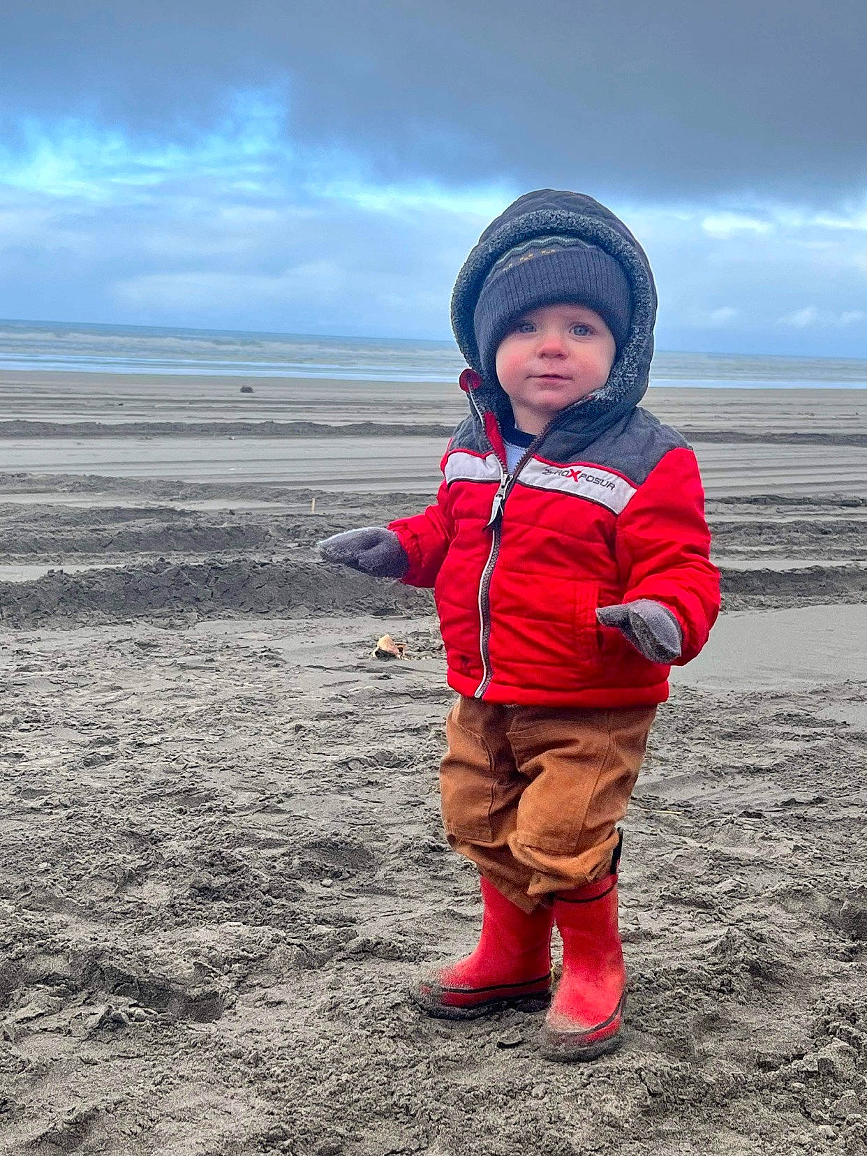 Maverick is registered to the contest to win money with this photo: child, cloud, coast, freezing, fun, grassland, happy, headwear, horizon, jacket, landscape, meteorological_phenomenon, ocean, people_in_nature, person, recreation, sand, sky, soil, toddler