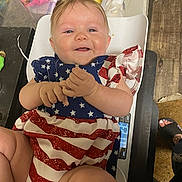 Ellieanna joined the competition — help win amazing prizes! baby, child, smiling, patriotic_clothing, stars_and_stripes, scale, indoor, person, clothing, feet, wooden_floor, hand, face, happy, furniture, footwear, diaper, human, skin, infant