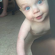 Emmett is registered to the contest to win money with this photo: baby, child, blue_eyes, crawling, carpet, indoor, person, face, hand, curious, skin, furniture, adult, legs, closeup, portrait, natural_light, expression, infant, human