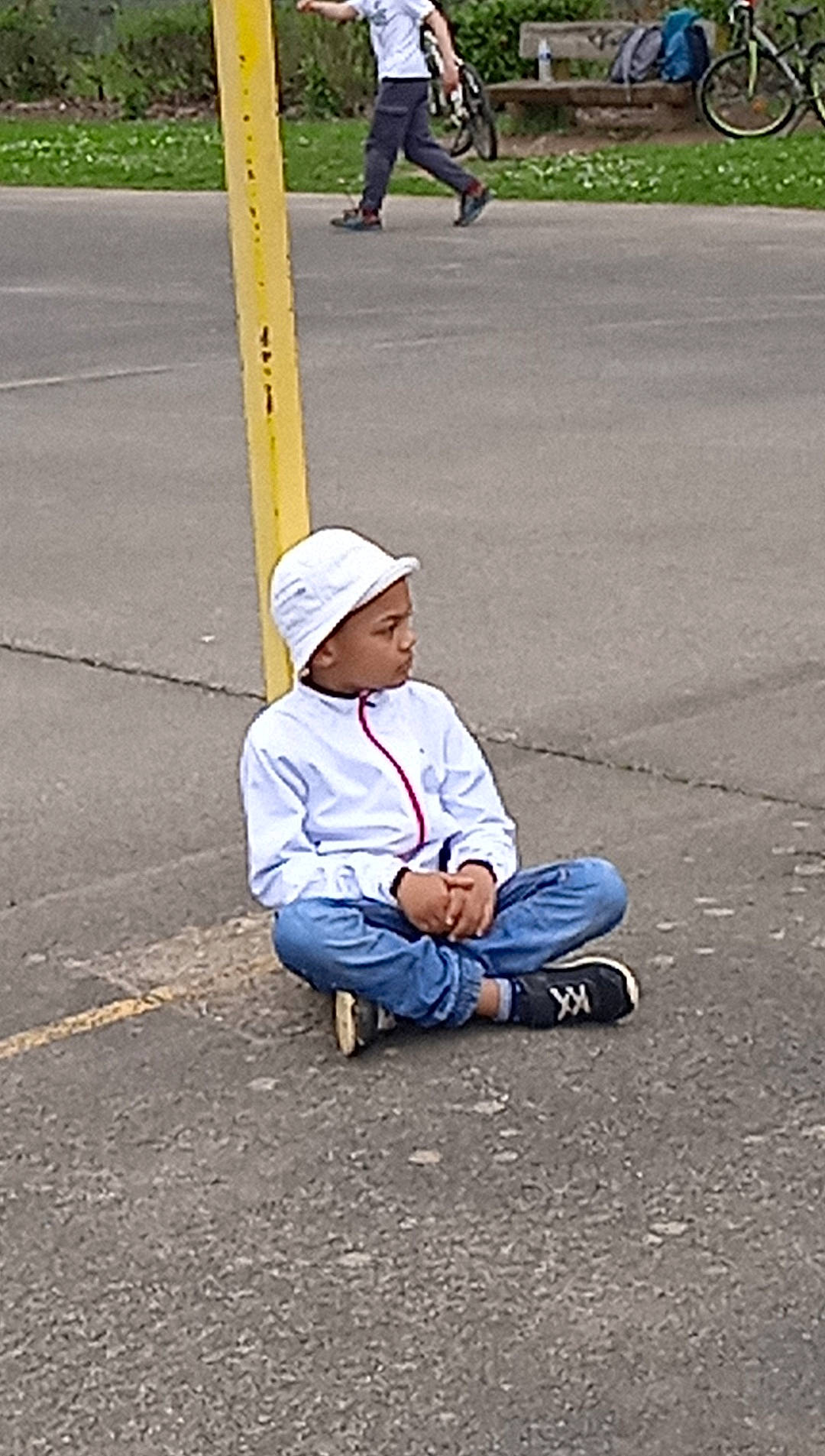 Hayden a rejoint le concours — aidez-le/la à gagner de superbes lots ! asphalt, cap, child, city, fun, grass, hat, headwear, human_leg, leg, leisure, pedestrian, person, recreation, road, road_surface, shadow, sidewalk, sitting, tire