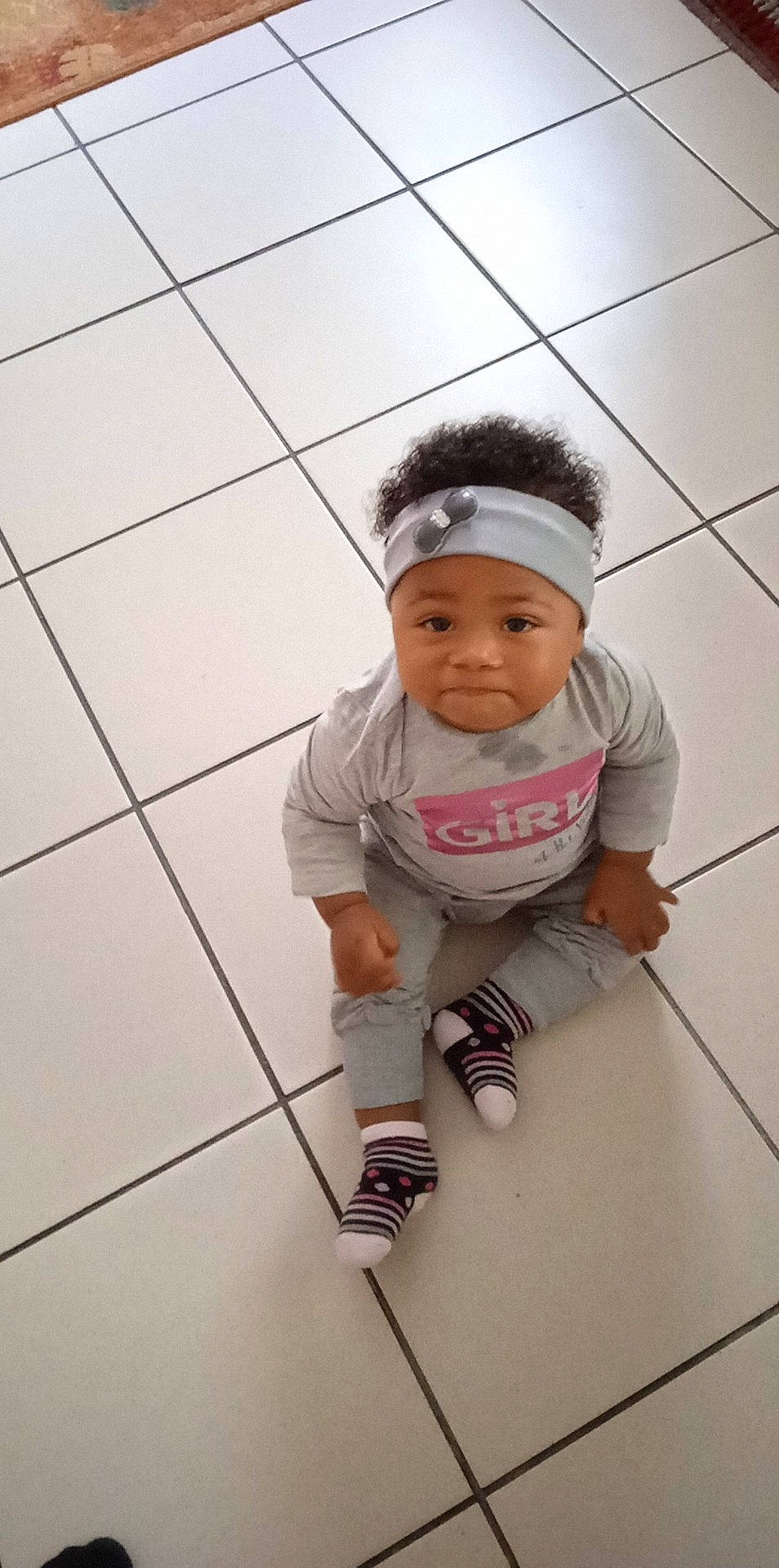 Elikya participe au concours pour gagner de l'argent avec cette photo : baby, baby_toddler_clothing, cap, child, eye, floor, flooring, fun, happy, headwear, knee, leg, pattern, person, personal_protective_equipment, portrait_photography, selfie, sitting, sleeve, sports_gear