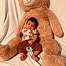 baby, teddy_bear, plush_toy, child, infant, soft_toy, brown_clothing, bear_pattern, cute, smiling, sitting, indoors, cozy, white_background, portrait, feet, happy, small_child, cuddly, toy