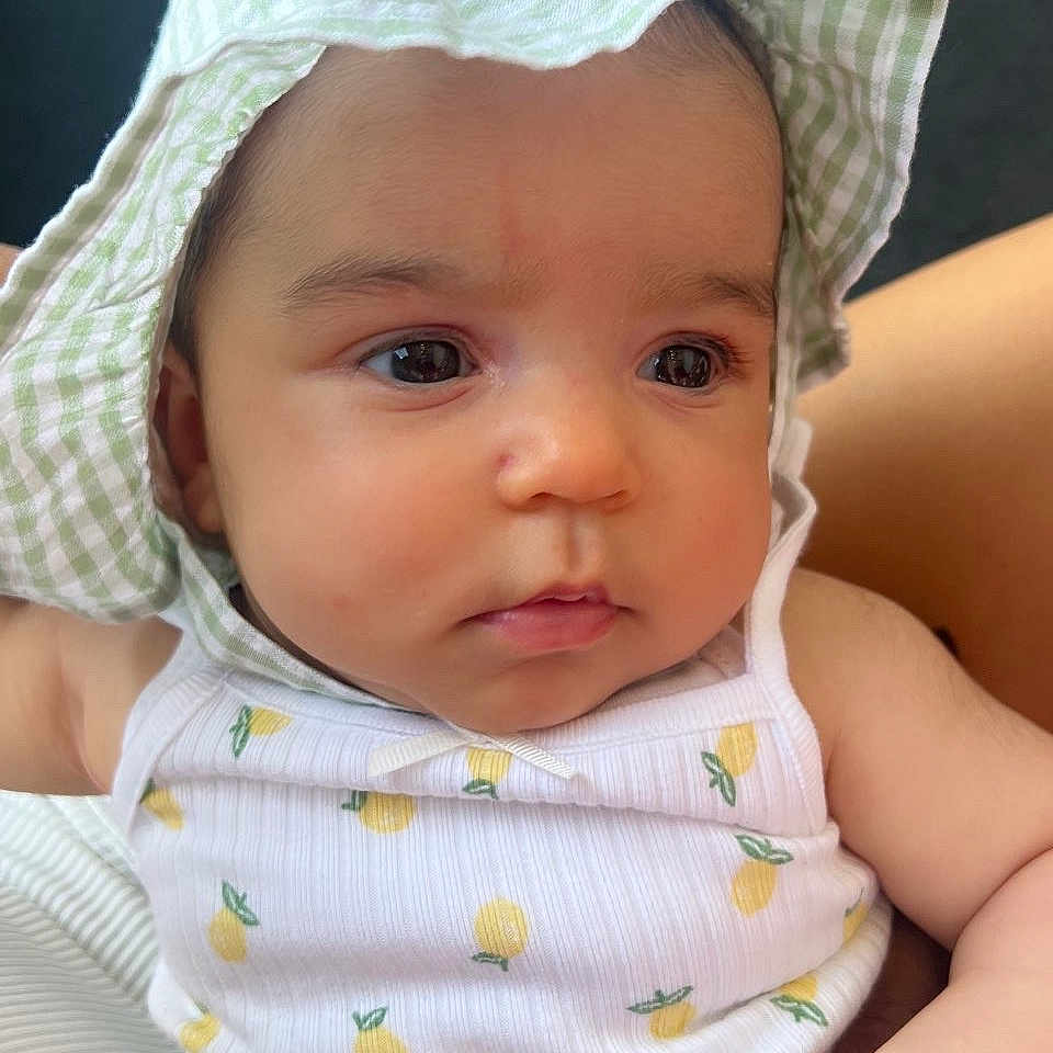 Nevaeh is registered to the contest to win money with this photo: baby, bonnet, cap, clothing, costume, dress, face, hat, head, newborn, person, photography, portrait, sitting, sunhat