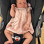 baby, infant, car_seat, pink_dress, pacifier, bracelet, footwear, child, seatbelt, indoor, floor_tiles, black_fabric, cute, person, newborn, resting, portrait, skin, hand, foot