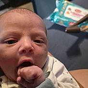 Ethan joined the competition — help win amazing prizes! awake, baby, child, close_up, couch, cozy, face, fist, hand, indoors, infant, mouth, newborn, photography, portrait, sitting, soft_lighting, star_pattern, white_clothing, wipes
