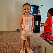 Melody joined the competition — help win amazing prizes! child, girl, unicorn_slippers, striped_outfit, carpet, living_room, television, photo_on_screen, smile, standing, hands_in_pockets, boy, red_shirt, toy, furniture, vase, flower, necklace, home_interior, playful