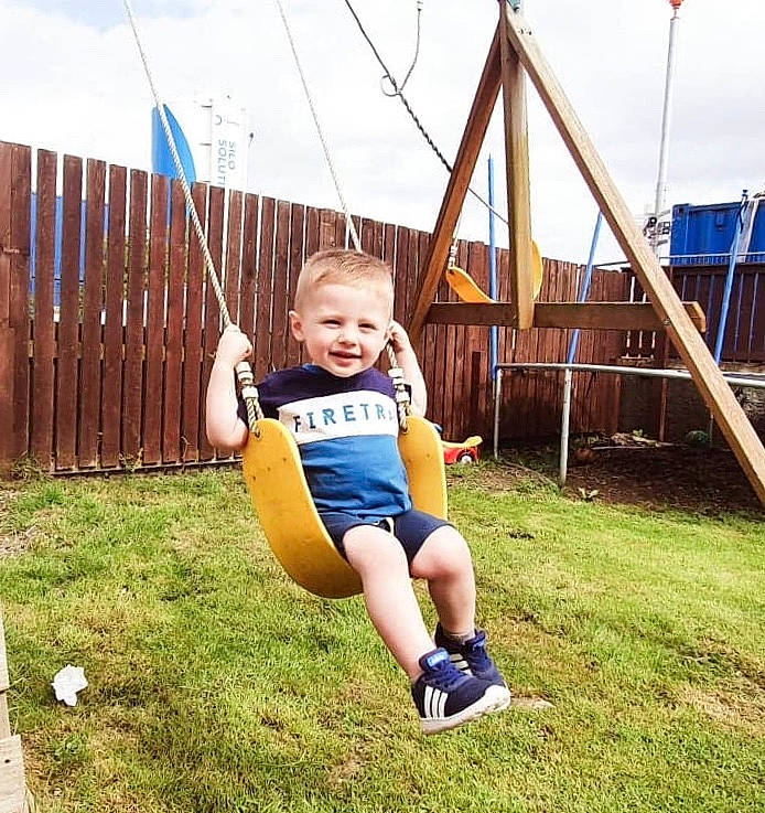 Teddie is registered to the contest to win money with this photo: child, fun, grass, joy, leisure, outdoor_play_equipment, person, play, playground, public_space, smile, swing, toddler, tree, vacation