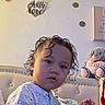 Jesiah joined the competition — help win amazing prizes! child, toddler, portrait, sitting, bedroom, bed, teddy_bear, plush_toy, curly_hair, short_hair, face, person, looking_at_camera, indoors, home, wall_decor, heart_decor, pajamas, cozy, photography