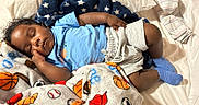 Prince is registered to the contest to win money with this photo: baby, sleeping, blanket, bed, blue_shirt, gray_shorts, socks, infant, cozy, soft, face, hand, child, cute, resting, comfort, home, indoors, peaceful, toddler