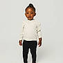 toddler, child, standing, barefoot, black_leggings, cream_sweater, braids, yellow_beads, studio, white_background, portrait, cute, fashion, young_child, person, smiling, innocent, happy, posing, full_body