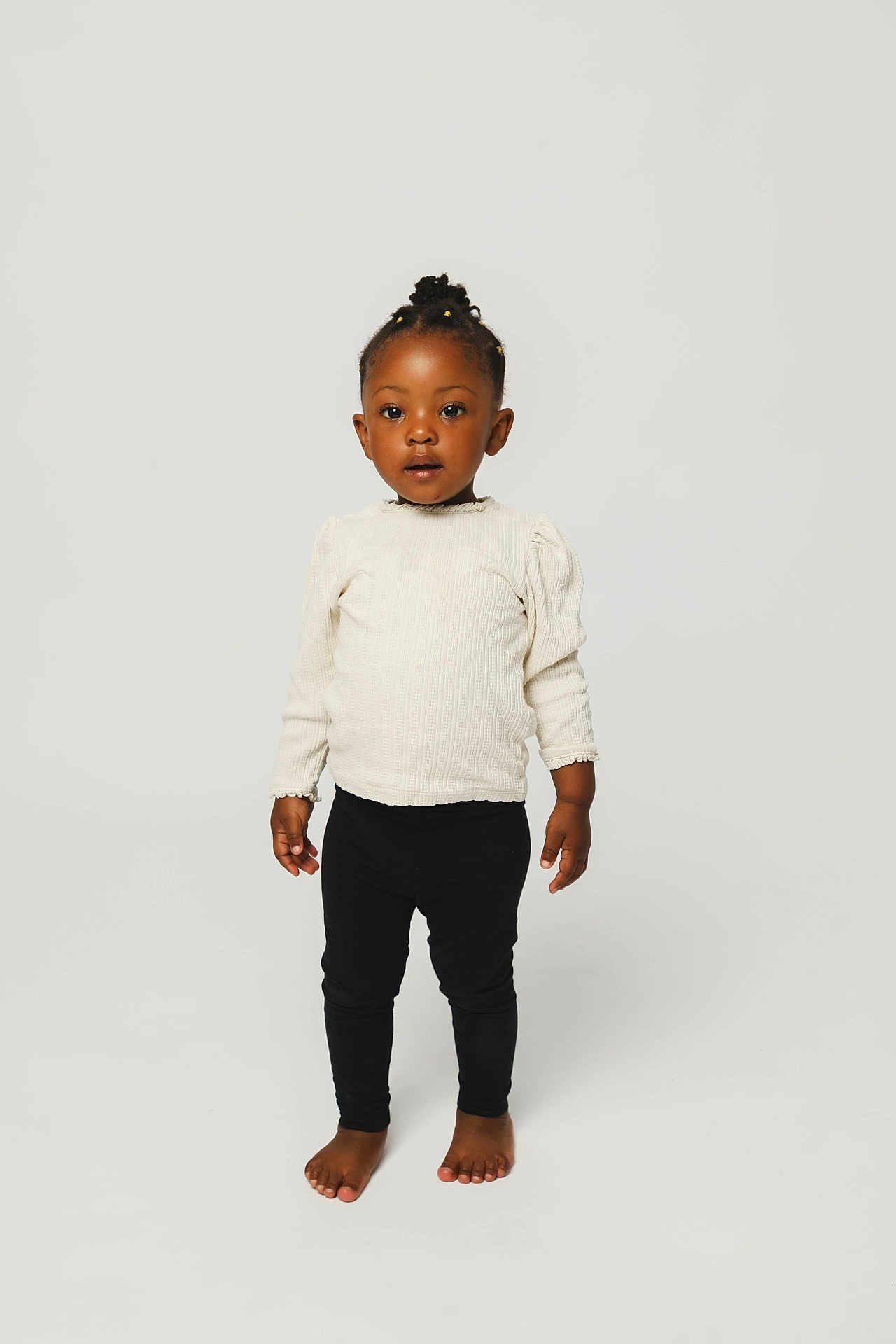 Jayleen participe au concours pour gagner de l'argent avec cette photo : toddler, child, standing, barefoot, black_leggings, cream_sweater, braids, yellow_beads, studio, white_background, portrait, cute, fashion, young_child, person, smiling, innocent, happy, posing, full_body