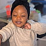 child, toddler, sweater, head_wrap, indoor, smiling, cute, person, face, expression, cozy, home, living_room, playful, portrait, young_child, happy, fashion, casual, skin