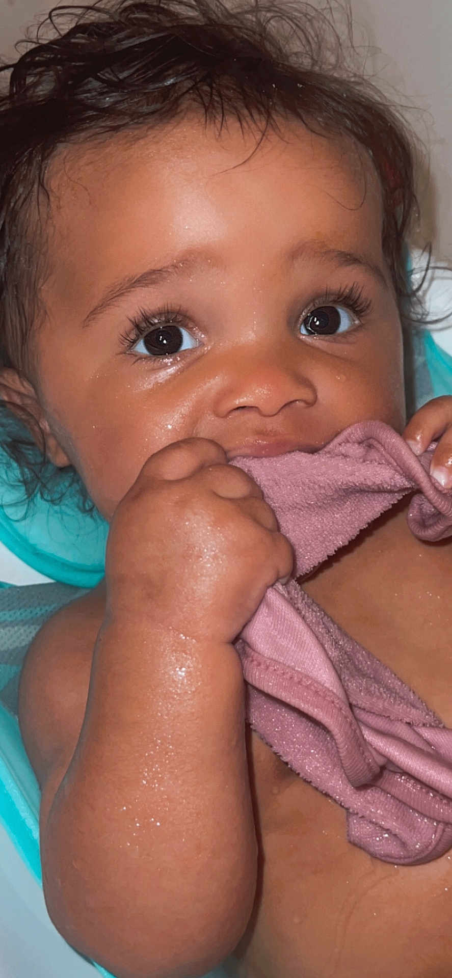 Avani is registered to the contest to win money with this photo: baby, close_up, wet_skin, pink_cloth, hand, face, curly_hair, large_eyes, bath_time, child, cute, skin, portrait, infant, grip, expression, indoors, young_child, toddler, playful