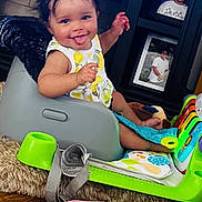 Avani joined the competition — help win amazing prizes! baby, child, smiling, tongue_out, baby_seat, toy, floor, wood_floor, photograph, frame, indoor, clothing, playtime, infant, happy, furniture, colorful, cushion, person, portrait