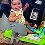 baby, child, smiling, tongue_out, baby_seat, toy, floor, wood_floor, photograph, frame, indoor, clothing, playtime, infant, happy, furniture, colorful, cushion, person, portrait