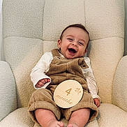 Raphaël participe au concours pour gagner de l'argent avec cette photo : baby, infant, smiling, happy, corduroy, overalls, white_shirt, armchair, cozy, cute, feet, toes, child, portrait, indoor, soft_texture, comfortable, light_skin, sitting, 4_months