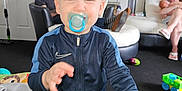 Jayden-Jamie is registered to the contest to win money with this photo: adult, baby, blanket, carpet, child, clothing, couch, family, furniture, home, indoor, living_room, man, pacifier, person, photography, smile, toddler, toys, woman