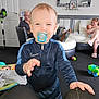 adult, baby, blanket, carpet, child, clothing, couch, family, furniture, home, indoor, living_room, man, pacifier, person, photography, smile, toddler, toys, woman