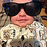 Paisley is registered to the contest to win money with this photo: baby, child, sunglasses, smile, onesie, animal_print, face, head, clothing, cute, infant, indoor, person, apparel, eyewear, fashion, portrait, young, happy, closeup