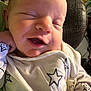 baby, infant, sleeping, smiling, face, onesie, star_pattern, hand, cushion, fabric, indoor, portrait, closeup, newborn, peaceful, cute, resting, child, soft_lighting, cozy