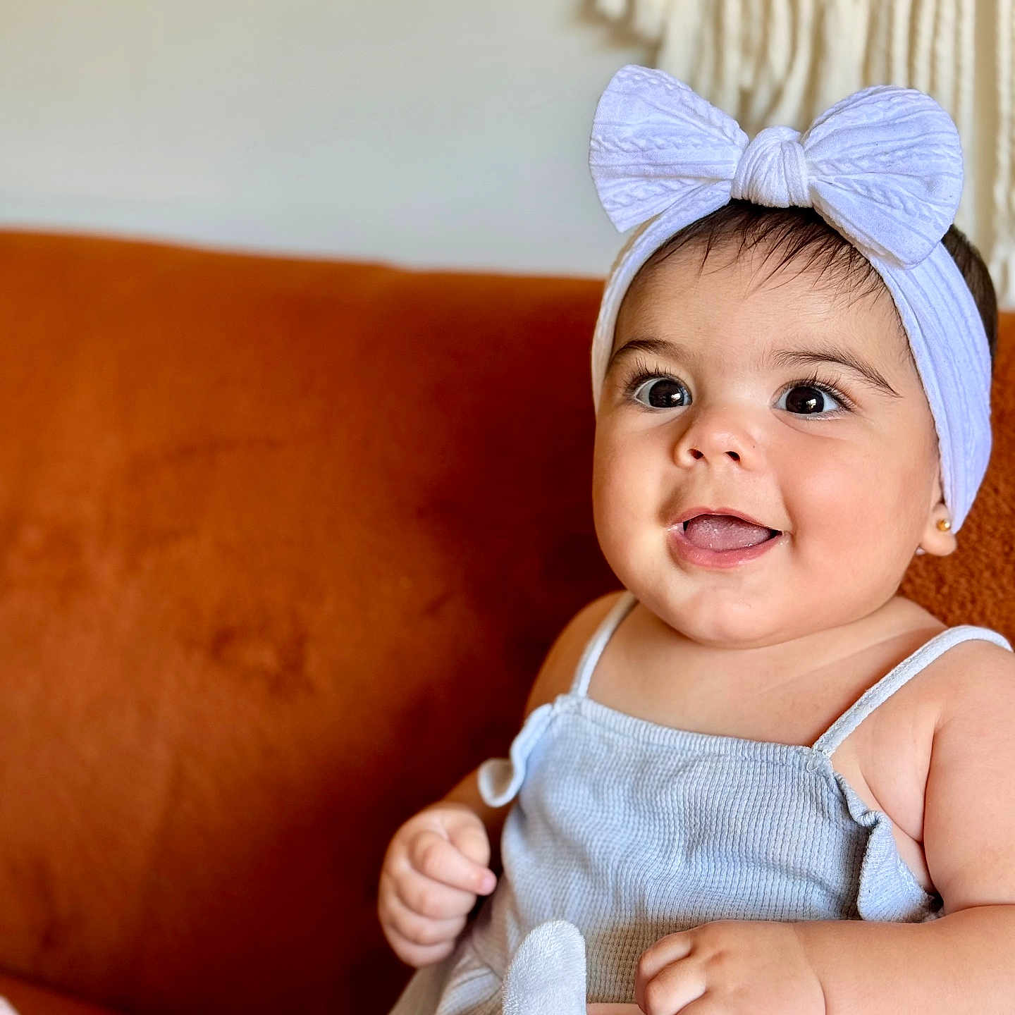 Lisa participe au concours pour gagner de l'argent avec cette photo : baby, blue_dress, bow, bright_eyes, child, couch, cute, face, girl, hand, happy, headband, indoors, infant, orange_couch, plush_toy, portrait, sitting, smiling, soft_toy