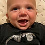 Rowan is registered to the contest to win money with this photo: baby, smiling, infant, black_clothing, batman_logo, onesie, happy, face, head, blue_eyes, seat, pattern, leaf_pattern, indoor, closeup, cute, person, child, soft_background, comfort