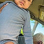 toddler, child, person, inside, car, holding, phone, clothing, long_sleeves, earrings, hand, tree, window, daylight, short_hair, jacket, denim, skin, face, portrait