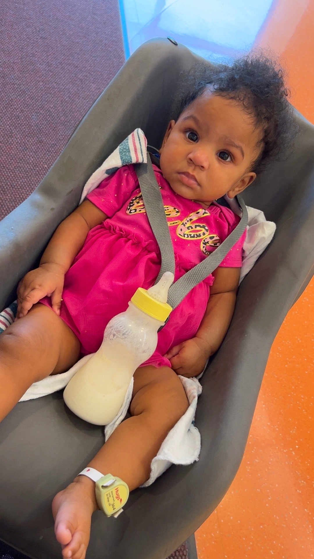 Brooklynn joined the competition — help win amazing prizes! baby, infant, milk_bottle, baby_seat, pink_clothing, hospital_wristband, curly_hair, indoors, car_seat, child, young_child, person, seatbelt, floor, carpet, orange_floor, toddler, cute, baby_girl, expression