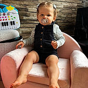 Summer participe au concours pour gagner de l'argent avec cette photo : toddler, child, pacifier, chair, plush_chair, black_romper, striped_shirt, hair_clips, toy_keyboard, wood_wall, indoor, floor, happy, cute, person, baby, feet, sitting, blue_eyes, home