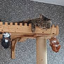 cat, tabby, wooden_platform, cat_tree, indoor, wallpaper, patterned_wall, relaxed, hanging_figurines, decor, pet, feline, resting, curious, whiskers, ears, claws, home, cozy, swinging