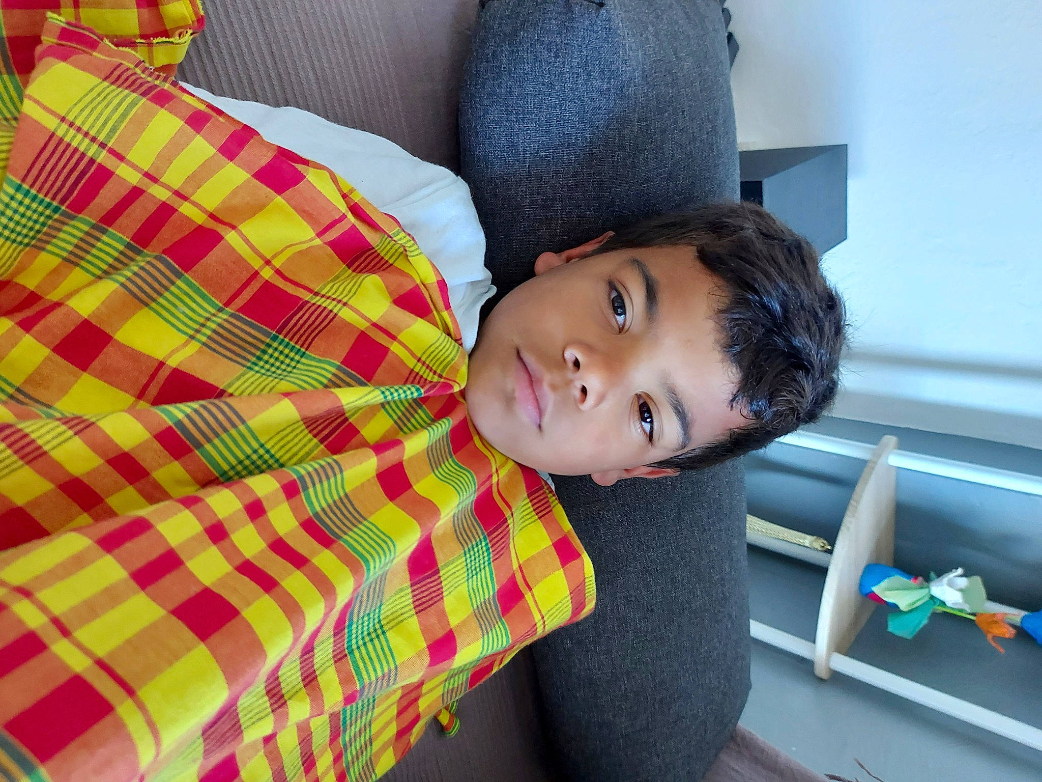 Kylian participe au concours pour gagner de l'argent avec cette photo : baby_toddler_clothing, child, collar, comfort, elbow, fun, happy, leisure, linens, magenta, neck, pattern, person, plaid, room, sitting, sleeve, t_shirt, tartan, thigh