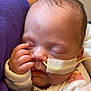 baby, blanket, closed_eyes, cozy, cute, face, feeding_tube, hand, hospital, indoors, infant, medical, newborn, person, purple_clothing, resting, skin, sleeping, soft, tissue_tape