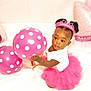 toddler, child, balloon, pink_tutu, tiara, polka_dots, birthday, celebration, indoor, cute, playing, smiling, happy, white_background, party, dress, sitting, portrait, african_american, toy