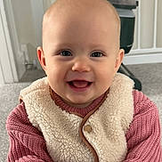 Ayla joined the competition — help win amazing prizes! baby, child, smiling, face, indoor, clothing, vest, sweater, carpet, person, cute, happy, portrait, young_child, infant, head, eyes, mouth, skin, furniture