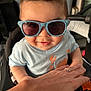 Jaxen joined the competition — help win amazing prizes! baby, background, blue, casual, child, clothing, cute, dinosaur_pattern, expression, face, fun, hand, indoor, light, person, seat, smile, sunglasses, toddler, toy