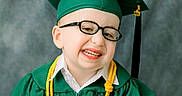 Brantley is registered to the contest to win money with this photo: child, graduate, green_gown, graduation_cap, diploma, glasses, smile, portrait, honor_cord, young_child, celebration, academic, studio_photo, happy, person, ceremony, formal_wear, indoors, face, tassel