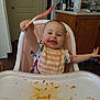 baby, high_chair, spoon, bib, messy, food, kitchen, cabinet, happy, smiling, child, person, indoor, tray, tableware, plastic, clothing, face, arm, wood_floor