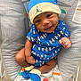 baby, infant, child, blue_clothing, hat, socks, smile, face, eyes, baby_seat, patterned_fabric, indoor, cute, happy, sitting, apparel, footwear, closeup, person, portrait