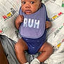 baby, infant, bib, purple_bib, blue_onesie, socks, blanket, train_pattern, bed, curious, cute, indoors, child, person, skin, face, legs, feet, clothing, laying_down