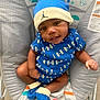 baby, infant, blue_clothing, hat, socks, baby_seat, patterned_seat, smiling, cute, child, indoors, elephant_toy, soft_toys, young_child, portrait, casual, comfortable, playful, close_up, seated
