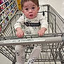 Daniel is registered to the contest to win money with this photo: baby, child, shopping_cart, pajamas, panda_pattern, grocery_store, aisle, floor, hand, face, eyes, clothing, infant, retail, seatbelt, cart_handle, store_shelves, product_boxes, curious, indoor