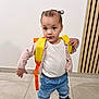 Lyah participe au concours pour gagner de l'argent avec cette photo : backpack, black_shoes, child, curious, denim, floor, indoor, orange, pants, person, pink_cardigan, shoes, standing, tiles, toddler, wall, white_shirt, wood_panel, yellow, young_child