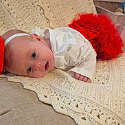Ariella joined the competition — help win amazing prizes! baby, infant, red_bow, red_skirt, white_shirt, blanket, crochet, chair, furniture, indoors, cute, portrait, face, headband, lying_down, skin, hand, foot, expression, curious