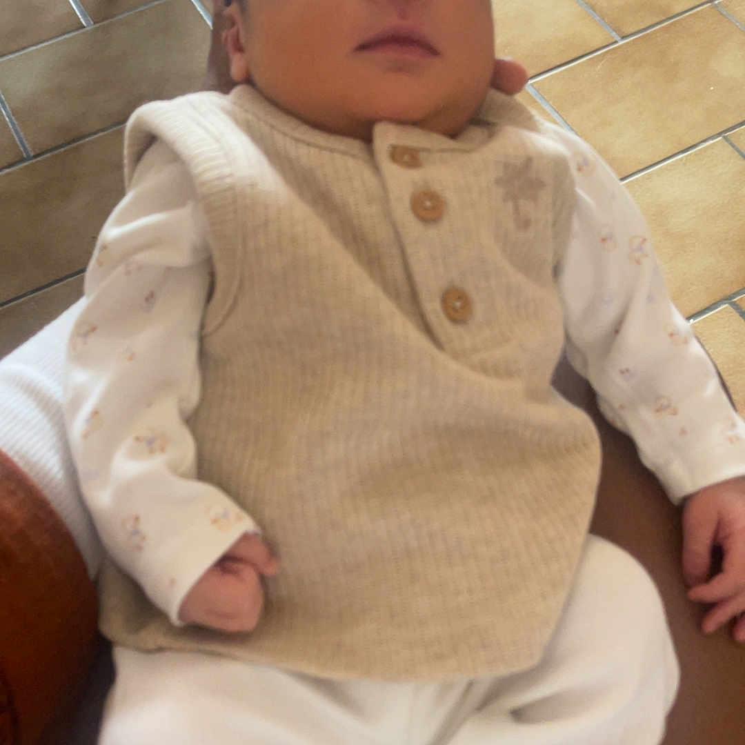 Soan Kayden a rejoint le concours — aidez-le/la à gagner de superbes lots ! baby, beige_vest, chair, closeup, clothing, cozy, floor, hand, indoor, infant, newborn, peaceful, person, portrait, resting, sleeping, soft_lighting, tile_floor, white_pants, wooden_chair