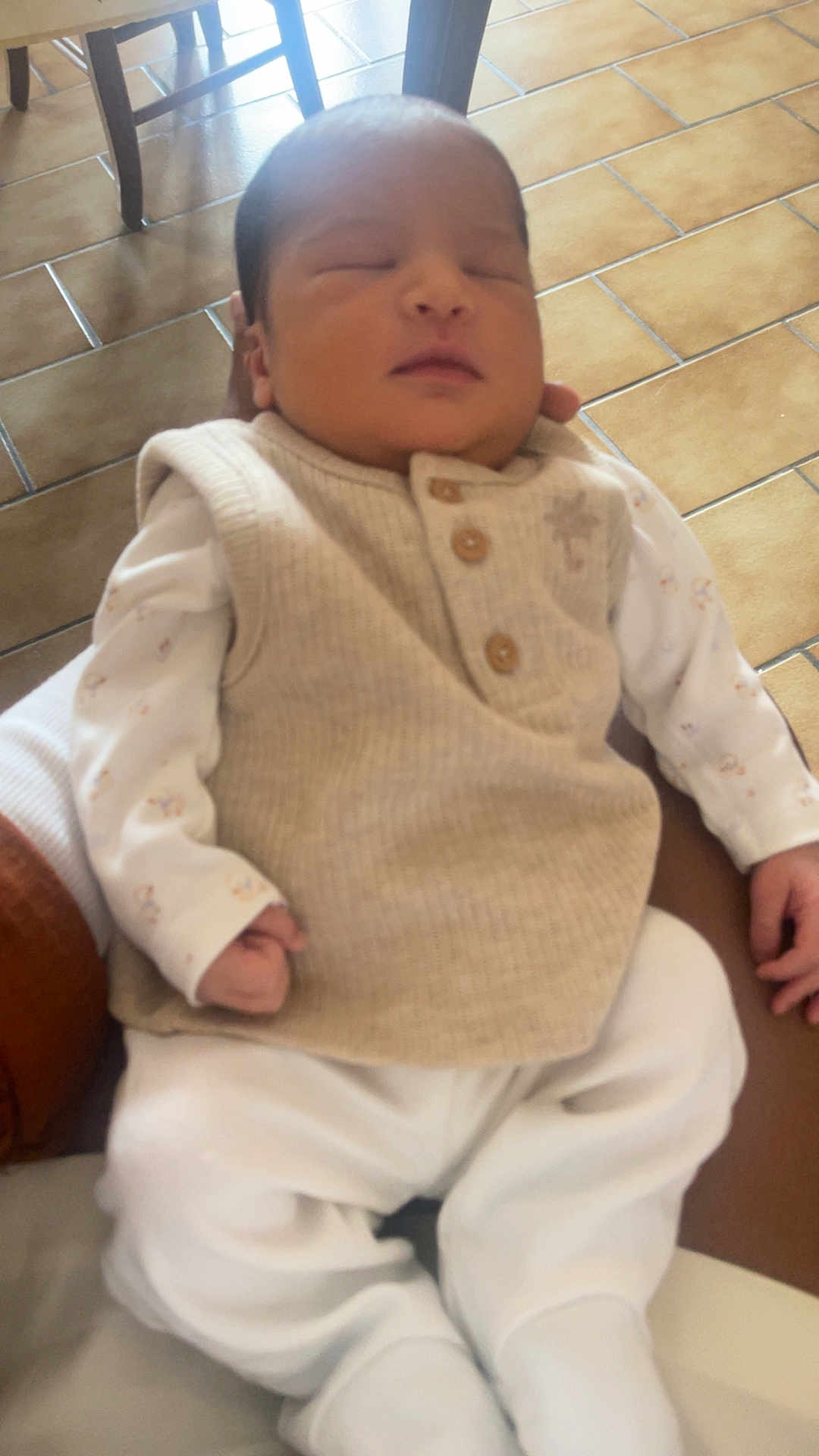 Soan Kayden a rejoint le concours — aidez-le/la à gagner de superbes lots ! newborn, baby, sleeping, infant, clothing, white_pants, beige_vest, person, hand, floor, tile_floor, chair, wooden_chair, indoor, cozy, resting, peaceful, soft_lighting, portrait, closeup