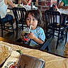 toddler, child, restaurant, drink, straw, table, napkin_holder, lime, brick_wall, chair, people, casual_clothing, indoor, food, dining, hairstyle, cup, window, background, young_child
