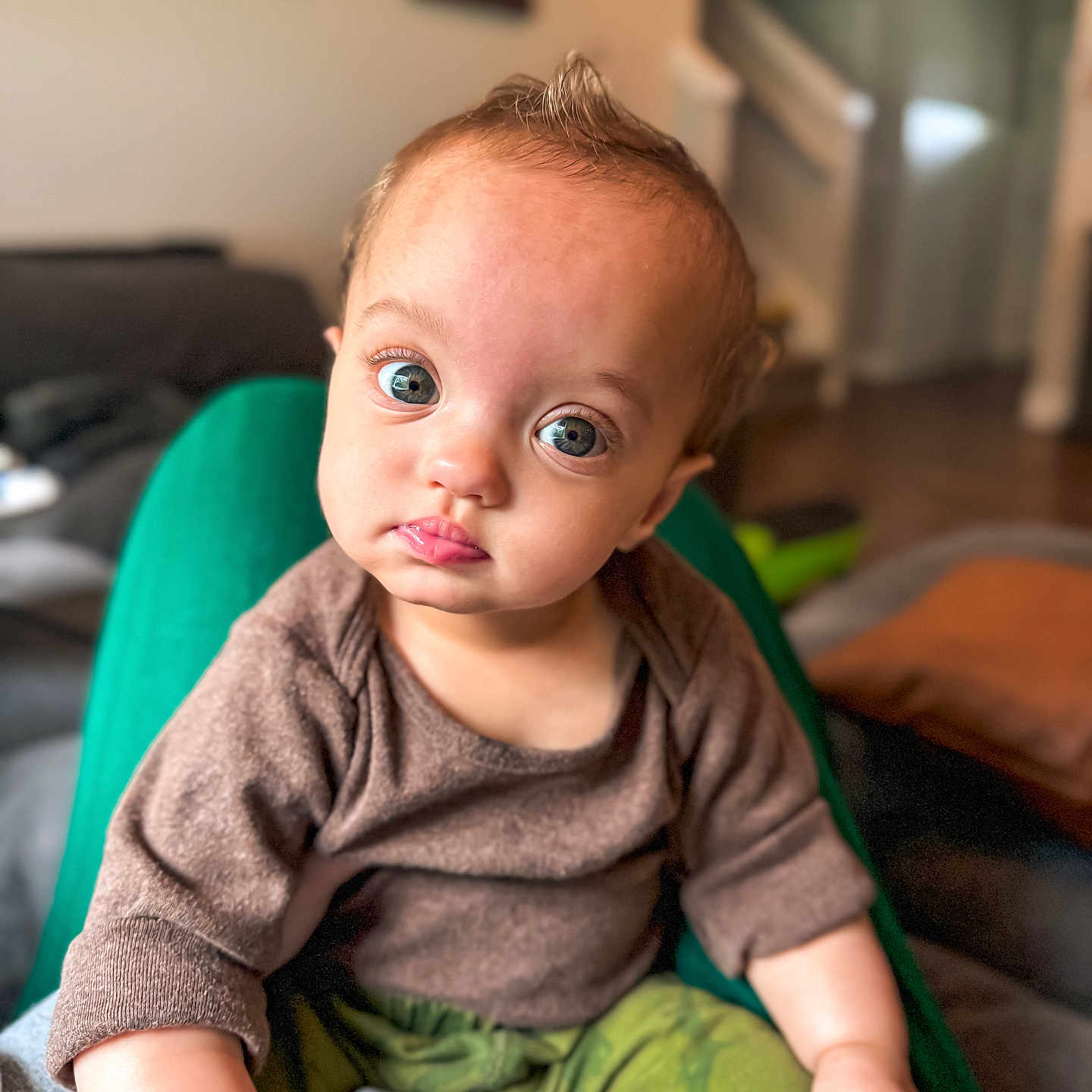 Ledger is registered to the contest to win money with this photo: baby, bodypart, clothing, couch, cushion, face, finger, furniture, hand, happy, head, homedecor, knitwear, pants, person, photography, portrait, sitting, smile, sweater